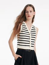 A lady wears a vest and black shorts.